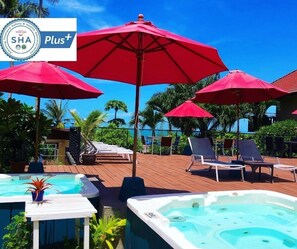 Relax by the pool surrounded by lush greenery and palm trees, with lounge chairs and a hot tub at your disposal.