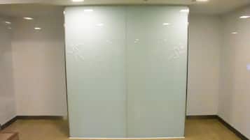A modern, enclosed elevator with a glass door and a logo indicating it is a women's restroom.