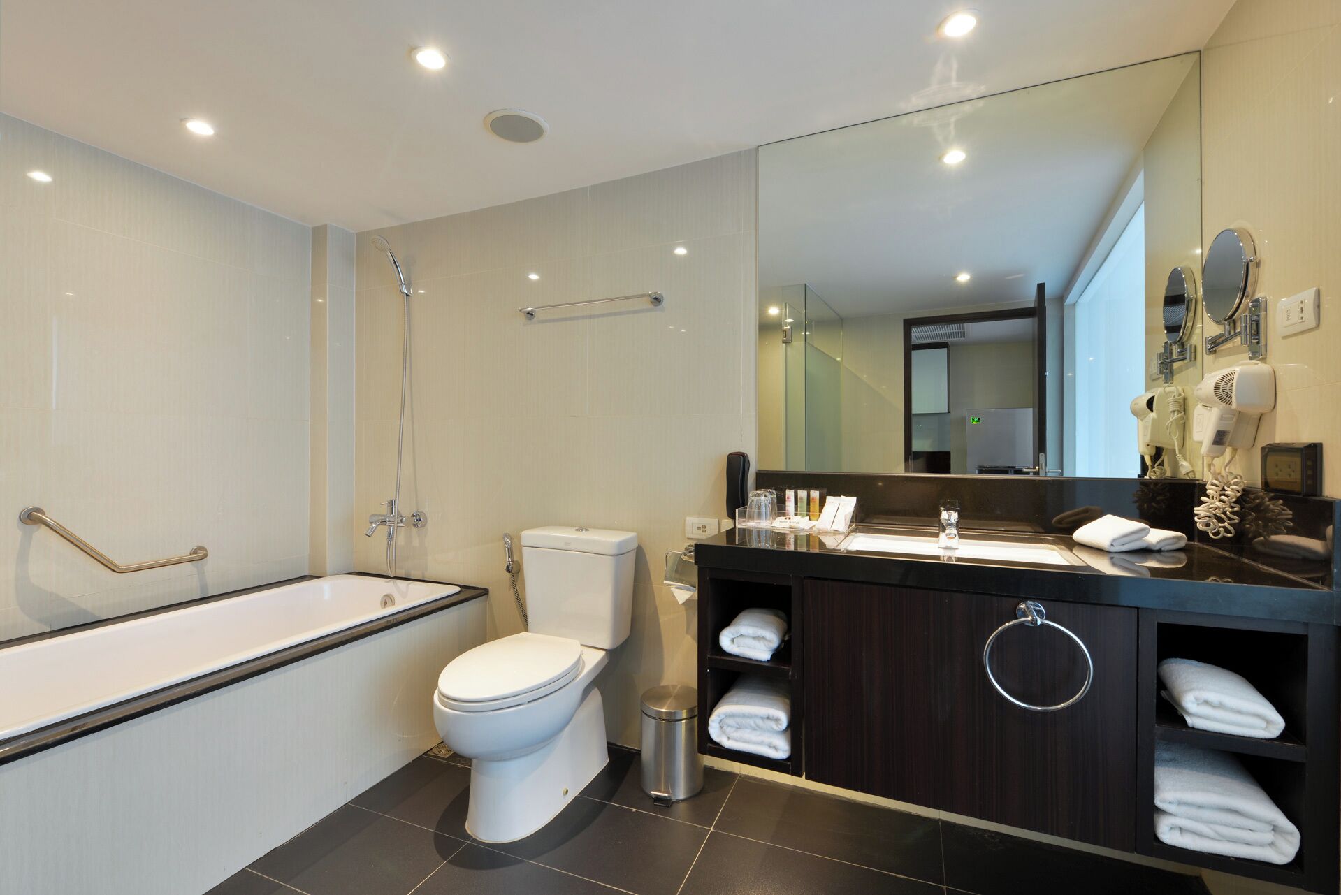 A modern bathroom with a bathtub, toilet, and vanity with a mirror.