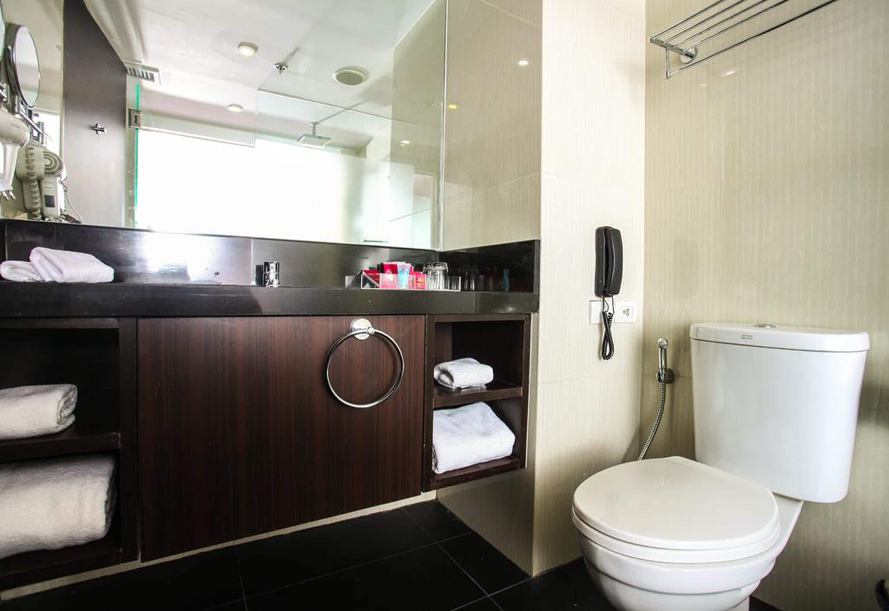 A modern bathroom with a dark wood vanity, a toilet, and a glass shower enclosure.