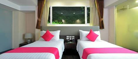 Habitación de hotel con dos camas, una ventana con cortinas, una mesita de noche con lámpara y vistas a zonas verdes.