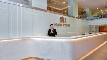 A reception desk at Hotel Royal with a modern design, a glass partition, and a digital display.