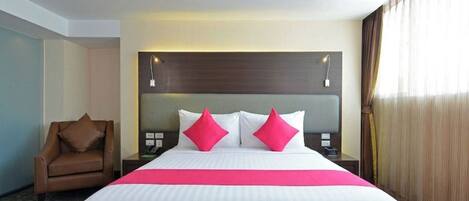 A hotel room with a large bed, two bedside tables, a chair, and a window with curtains.