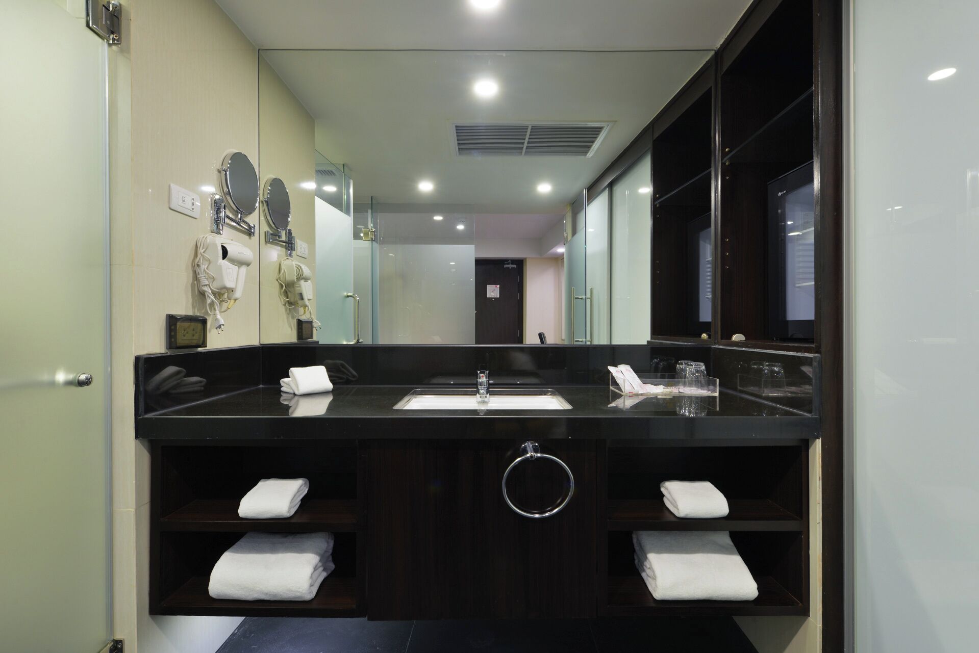 Un bagno moderno con un grande specchio, due lavandini e un portasciugamani.