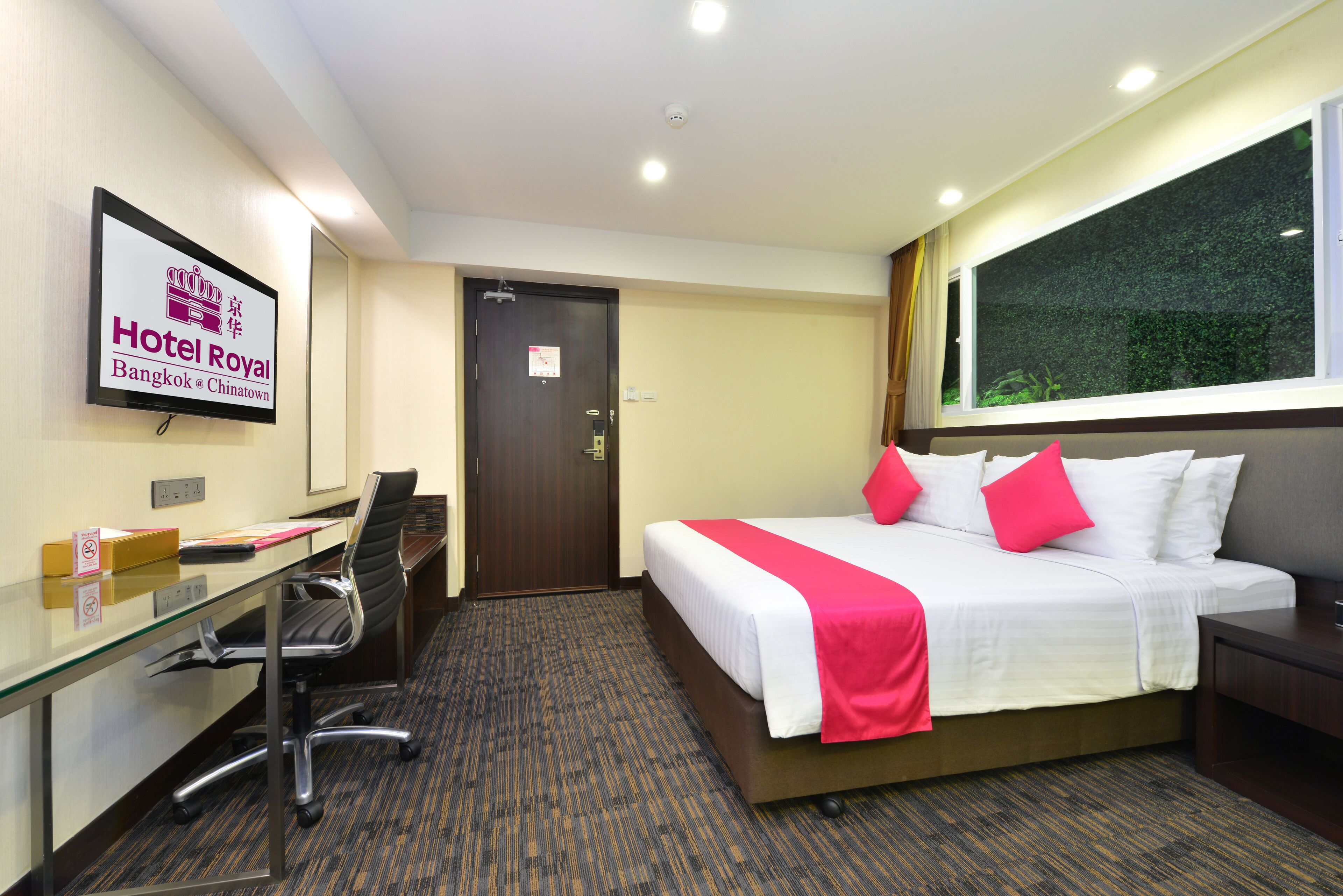 Una habitación de hotel con cama, escritorio, silla y ventana.