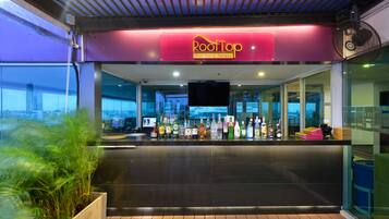 A bar area with a sign reading "RootTop Pool Bar & Terrace" and a variety of bottles on the counter.