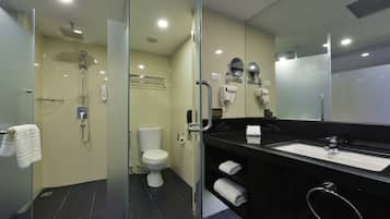 A modern bathroom with a glass-enclosed shower, a toilet, and a sink with a towel rack.