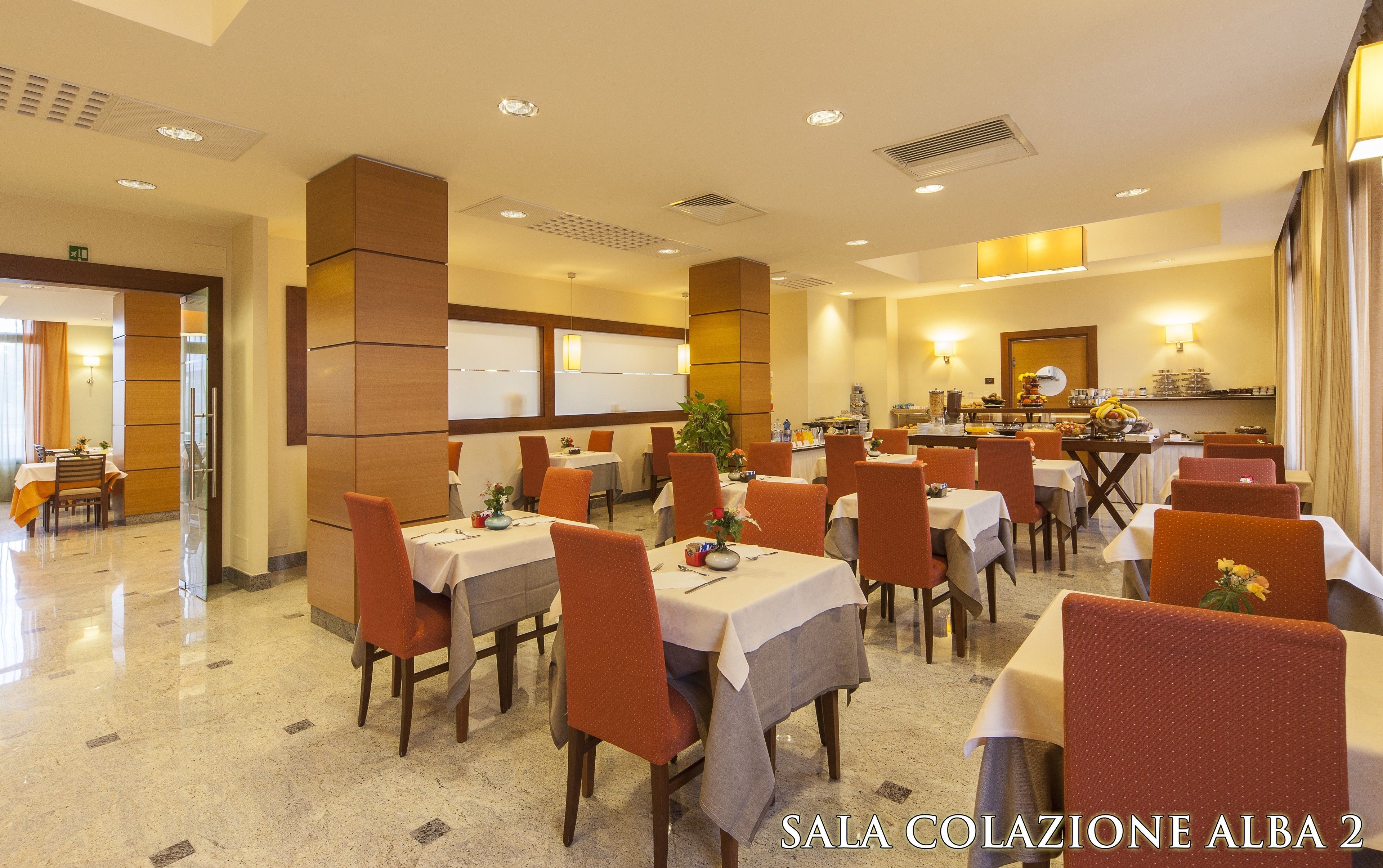 Un comedor de hotel con varias mesas y sillas, una barra de buffet y un reloj en la pared.