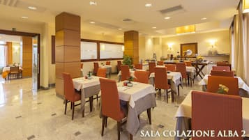 A hotel dining area with multiple tables and chairs, a buffet setup, and a clock on the wall.