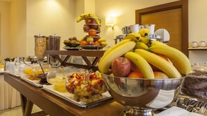 A buffet with various fruits, a fruit bowl, and a coffee station. - NilHotel Florence (Florence)