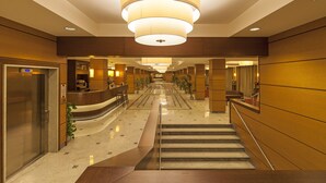 A hotel lobby with a reception desk, a staircase, and a large chandelier. - NilHotel Florence (Florence)