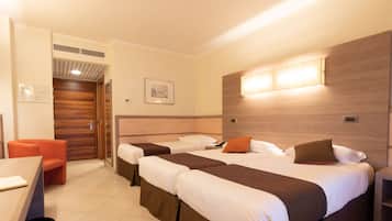 A hotel room with two beds, a desk, and a chair.