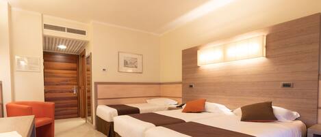 A hotel room with two beds, a desk, and a chair.