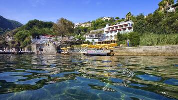 Ein Hotel am Wasser mit klarem Wasser, einer Anlegestelle und Gebäuden an einem Hügelhang.