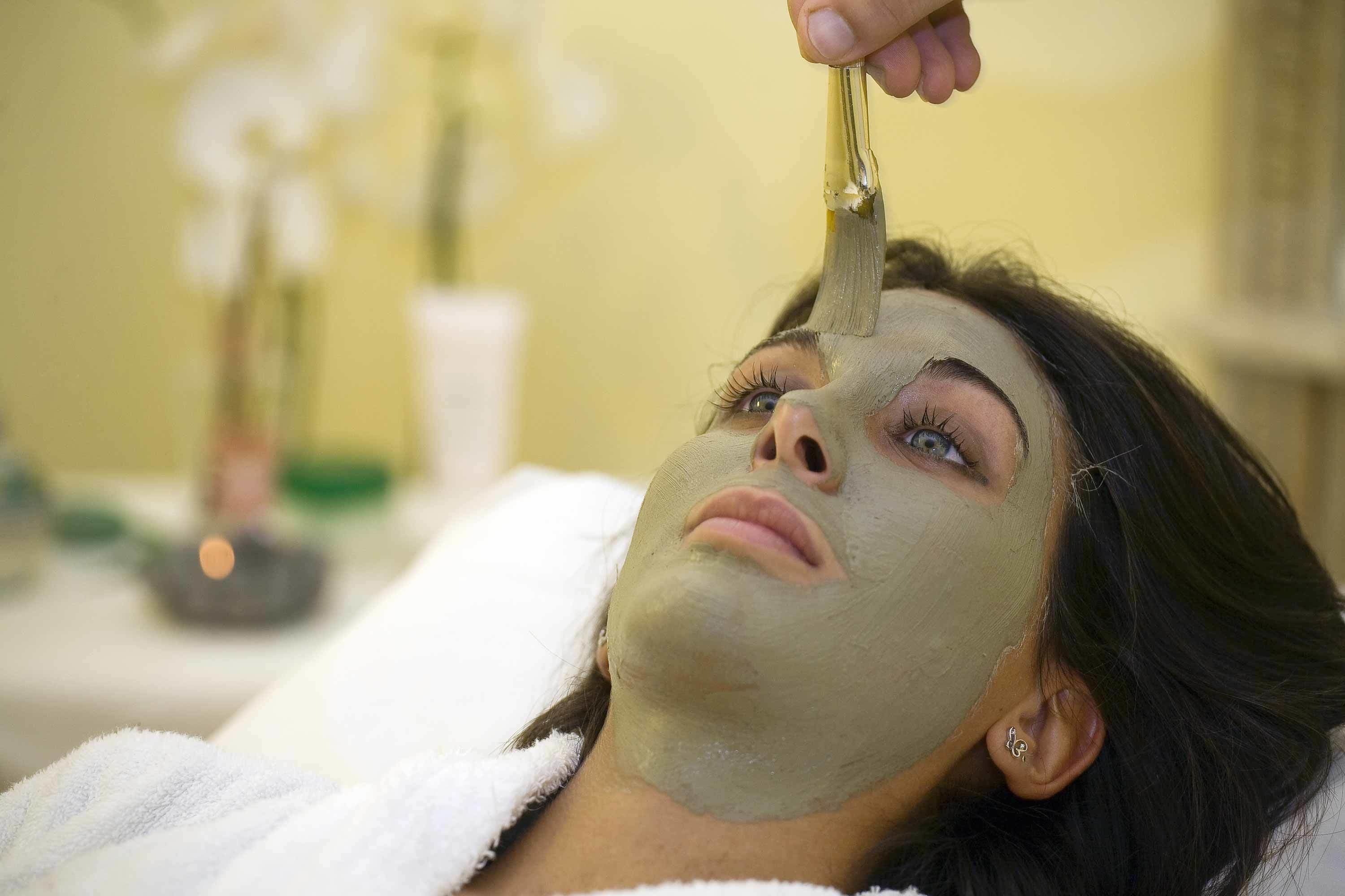Iemand ontvangt een gezichtsbehandeling met een masker op het gezicht.