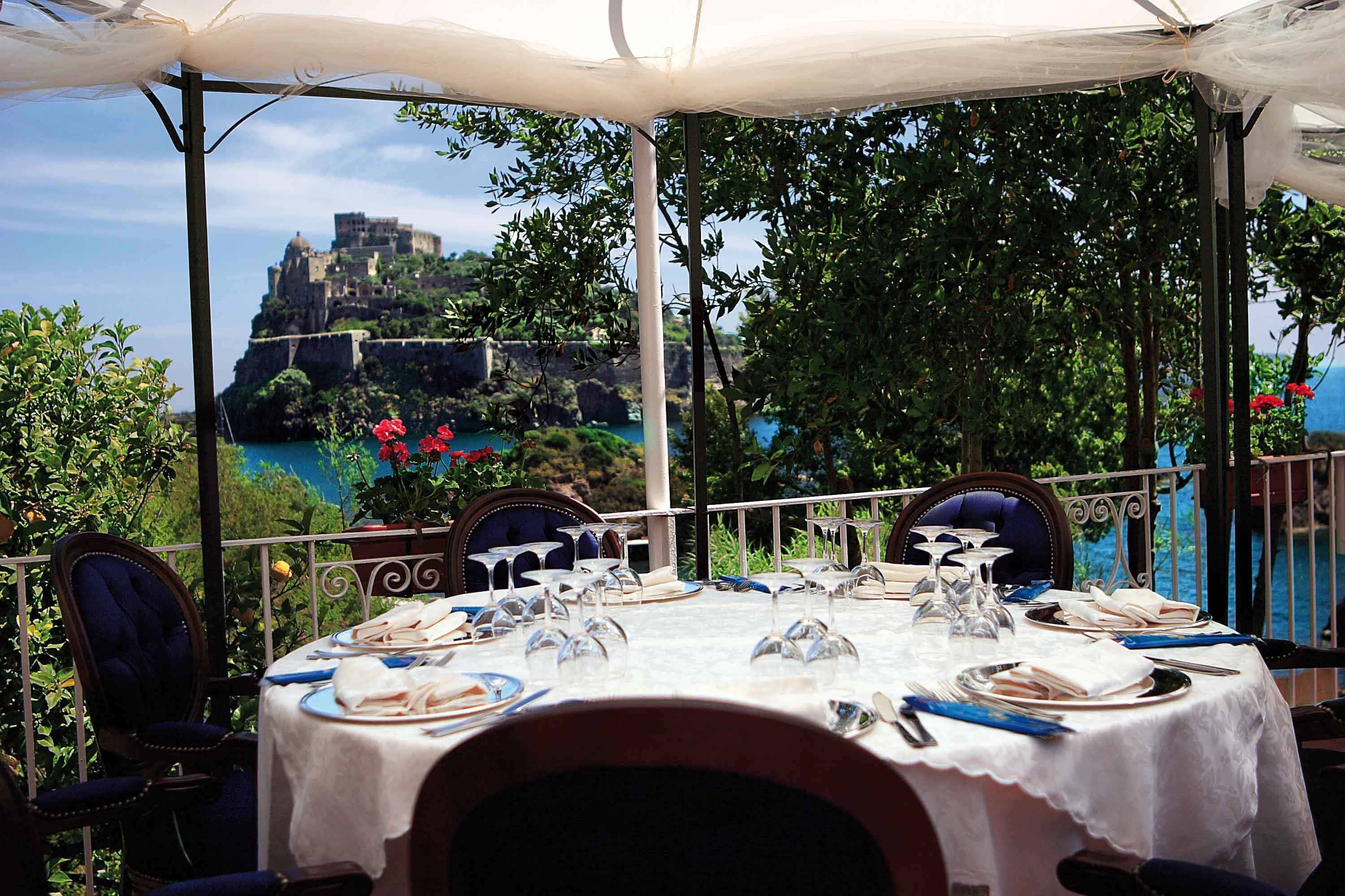 A table set for dining with a view of a historic castle on a hill.