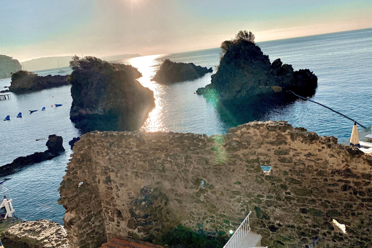 A coastal scene with rocky formations and clear blue water.