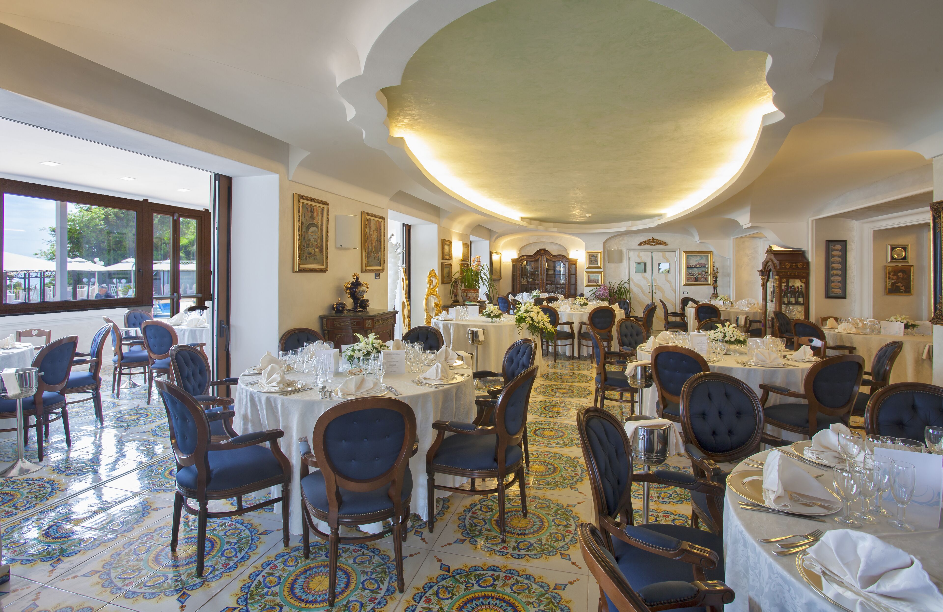 A dining area with round tables, blue upholstered chairs, and patterned floor tiles.