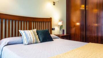 A neatly made bed with a blue bedspread and a decorative throw blanket.