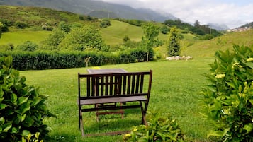 Un banc dans un champ verdoyant, avec des montagnes en arrière-plan.