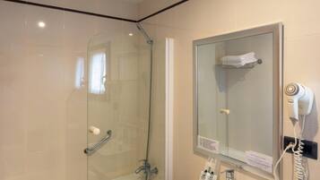 Een moderne badkamer met een douchecabine van glas, een witte wastafel en een haardroger bevestigd aan de muur.