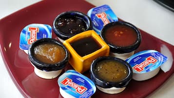 Une assiette contenant différentes sauces, notamment de la moutarde, du ketchup et de la mayonnaise.