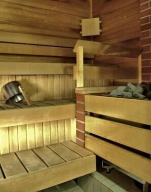 A sauna with wooden benches and a metal bucket. - Hotel Kuninkaantie (Espoo)