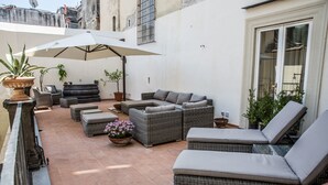 A patio with wicker furniture, a large umbrella, and potted plants. - Decumani Hotel De Charme (Naples)