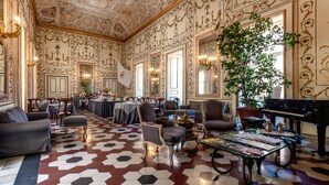 A spacious room with a patterned floor, elegant furniture, and a grand piano. - Decumani Hotel De Charme (Naples)
