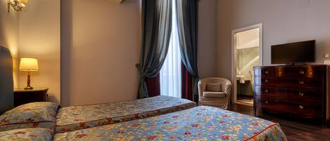Habitación de hotel con dos camas, un aparador, un televisor y una silla.