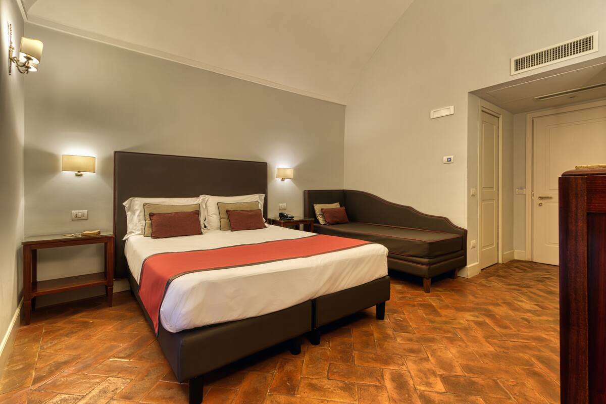 Ein Hotelzimmer mit einem großen Bett, einer Couch und einem Nachttisch mit Lampen.