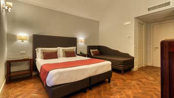 Une chambre d’hôtel comprenant un lit, des tables de chevet, un canapé et une armoire.