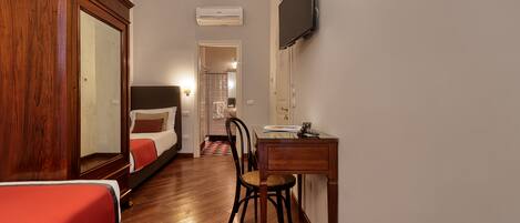 A hotel room with a bed, a desk, a chair, a TV, and a mirror.