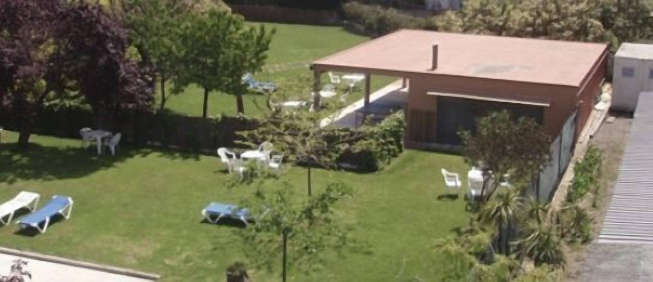 Un espacio al aire libre techado, rodeado de césped y árboles.