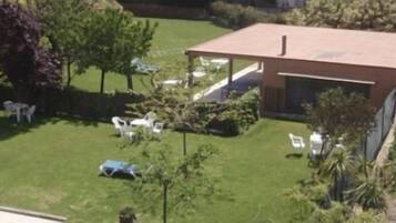 Un espacio al aire libre techado, rodeado de césped y árboles.
