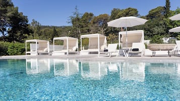 Una piscina al aire libre, sombrillas, tumbonas