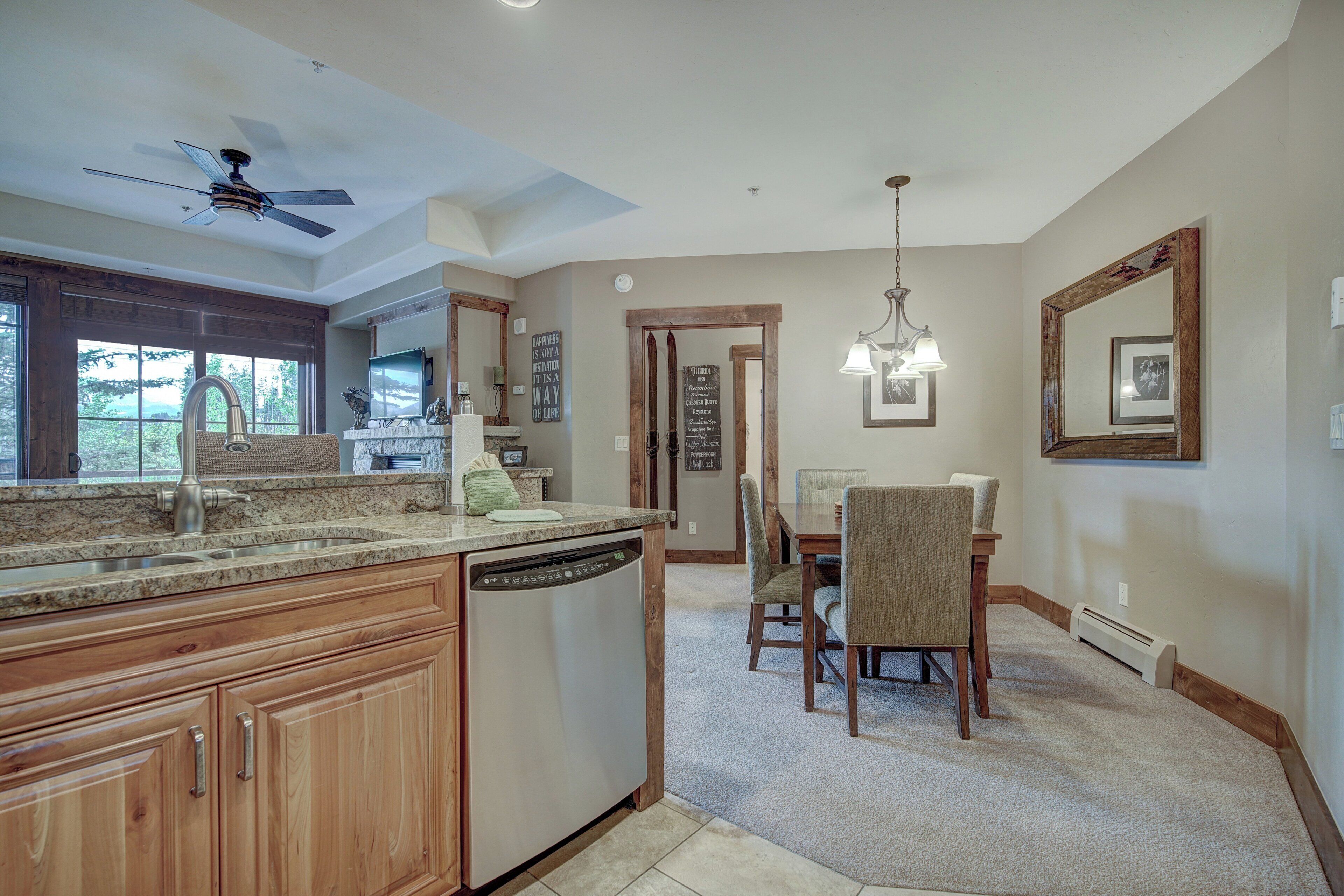 A kitchen with wooden cabinets, a dishwasher, and a dining area with a table and chairs.