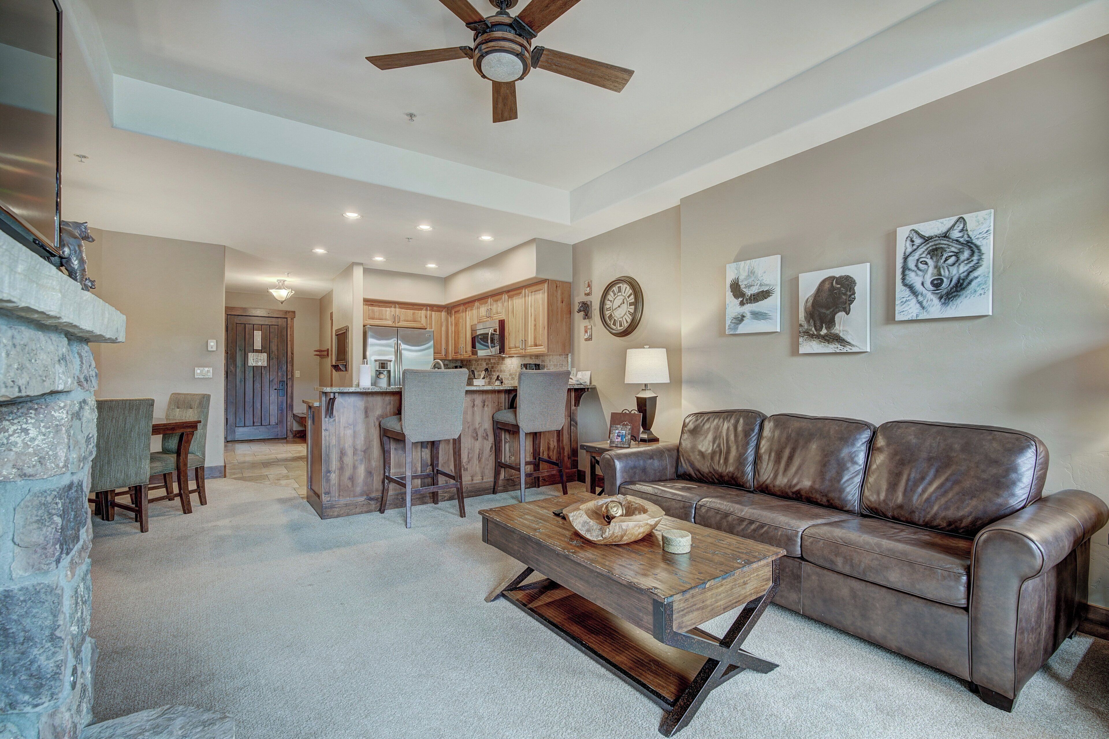 A spacious living room with a leather sofa, a wooden coffee table, and a stone fireplace.