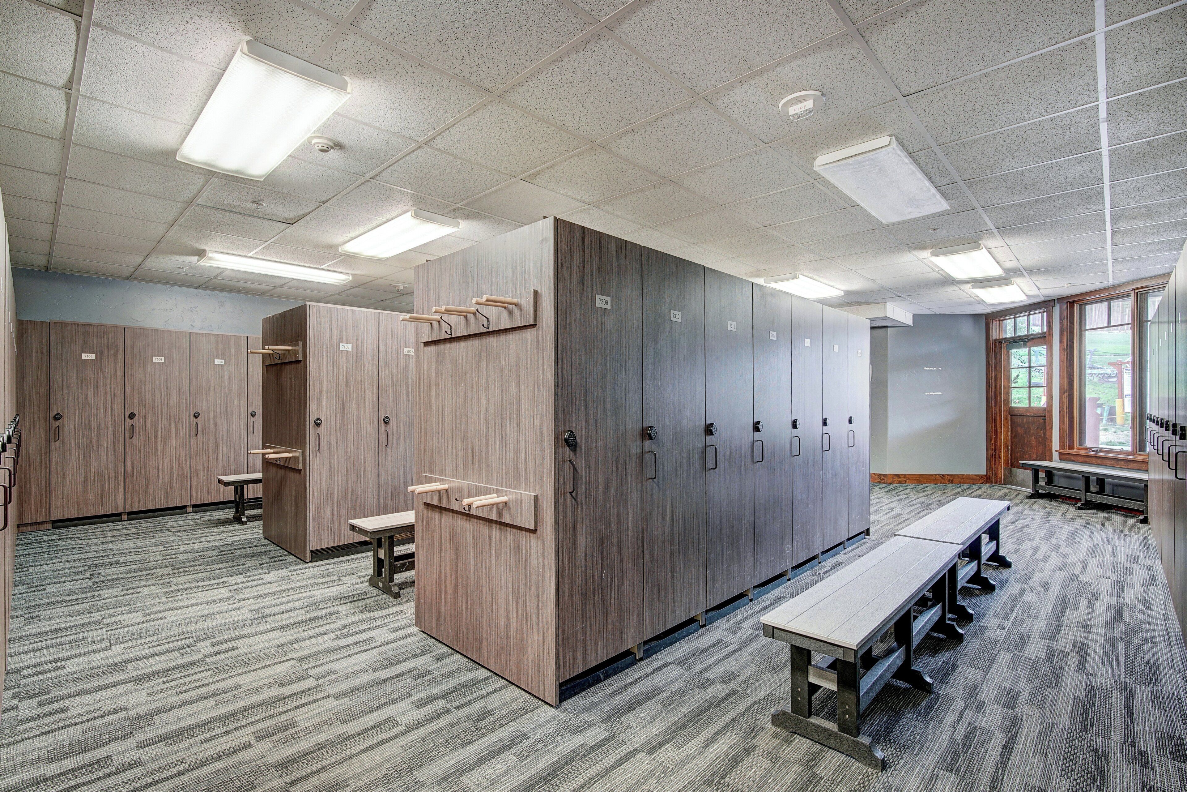 A locker room with multiple lockers, benches, and a tiled floor.