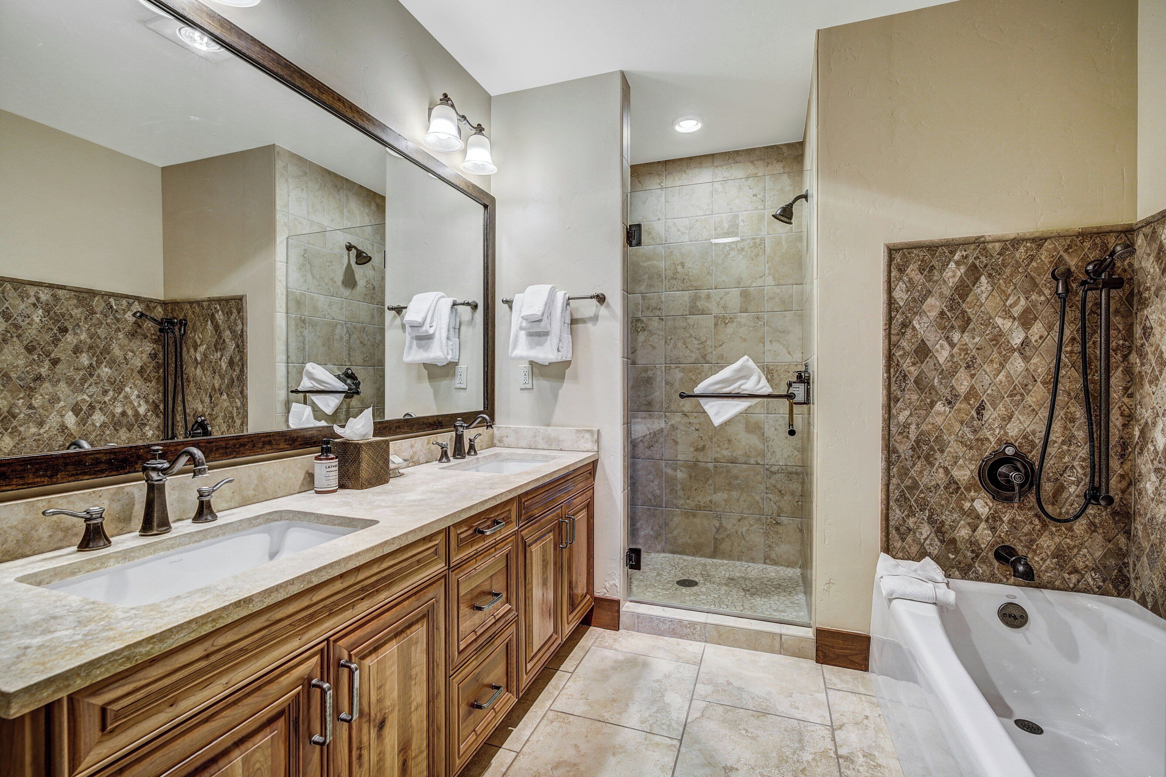 A bathroom with two sinks, a large mirror, a shower, and a bathtub.