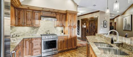 Una cocina con armarios de madera, pileta de acero inoxidable y encimeras de granito.