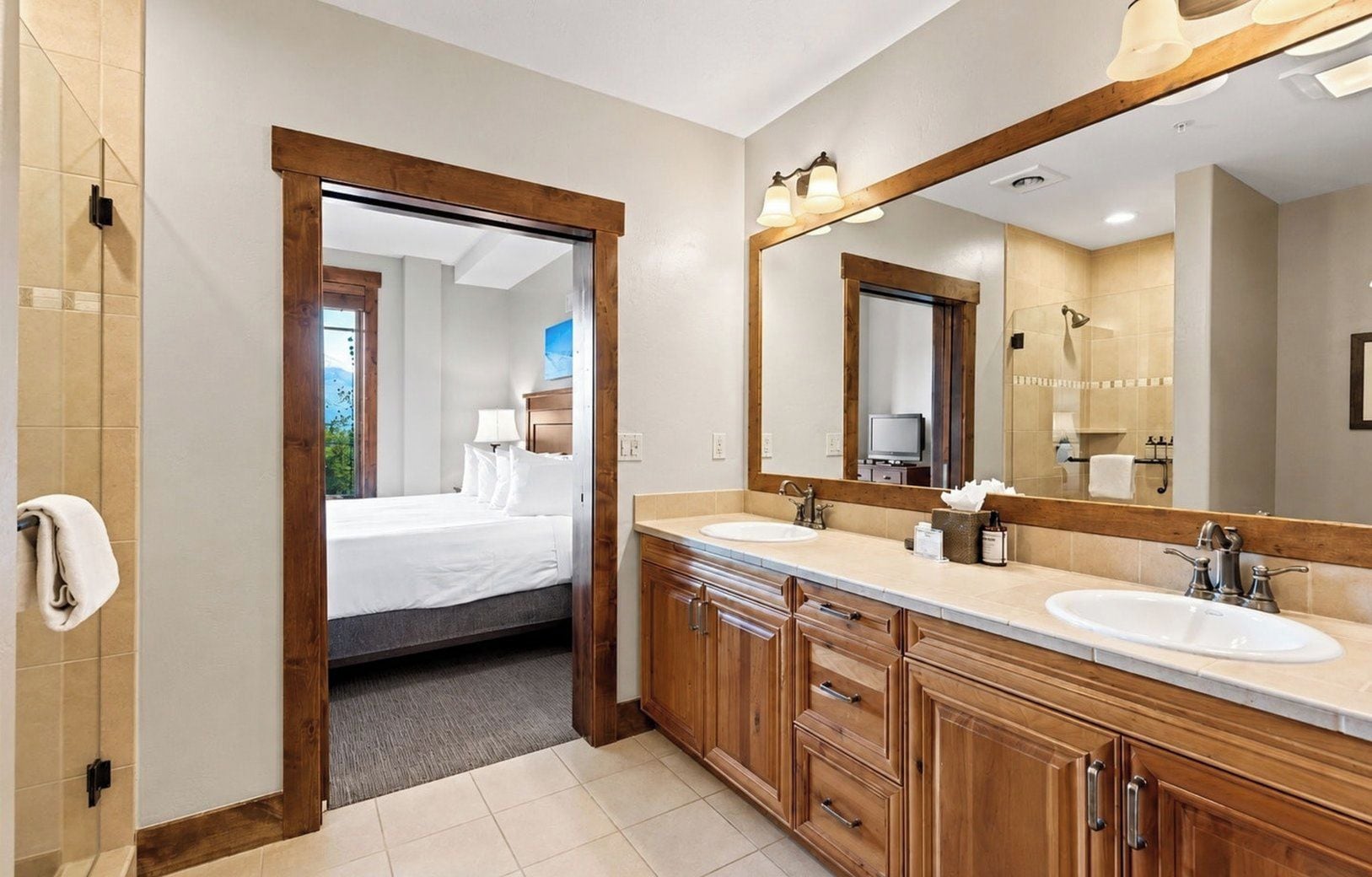 Un baño moderno con armarios de madera, un lavabo doble y un espejo grande.