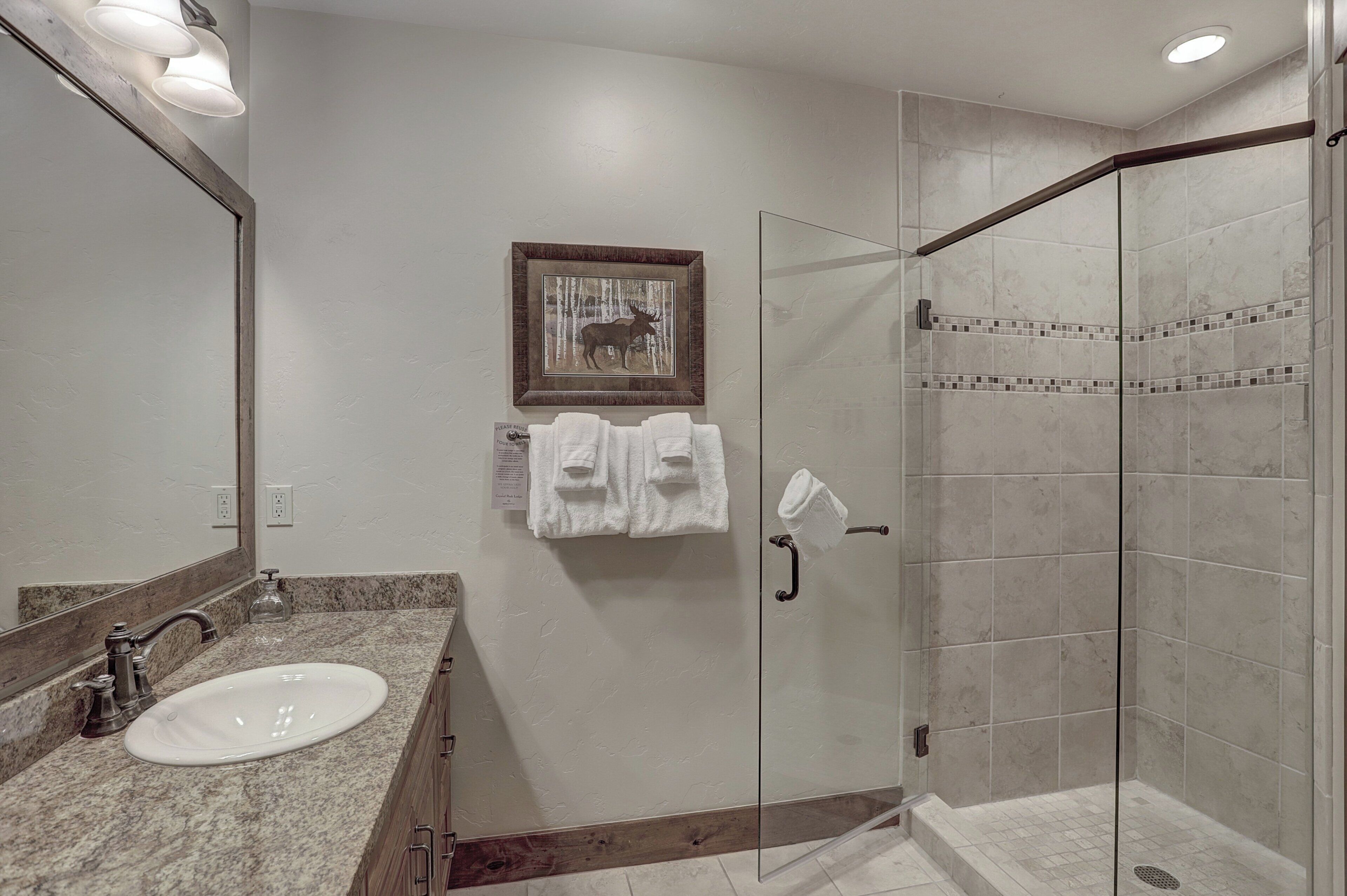 Une salle de bain équipée d’un lavabo, d’un miroir et d’une douche à parois de verre.