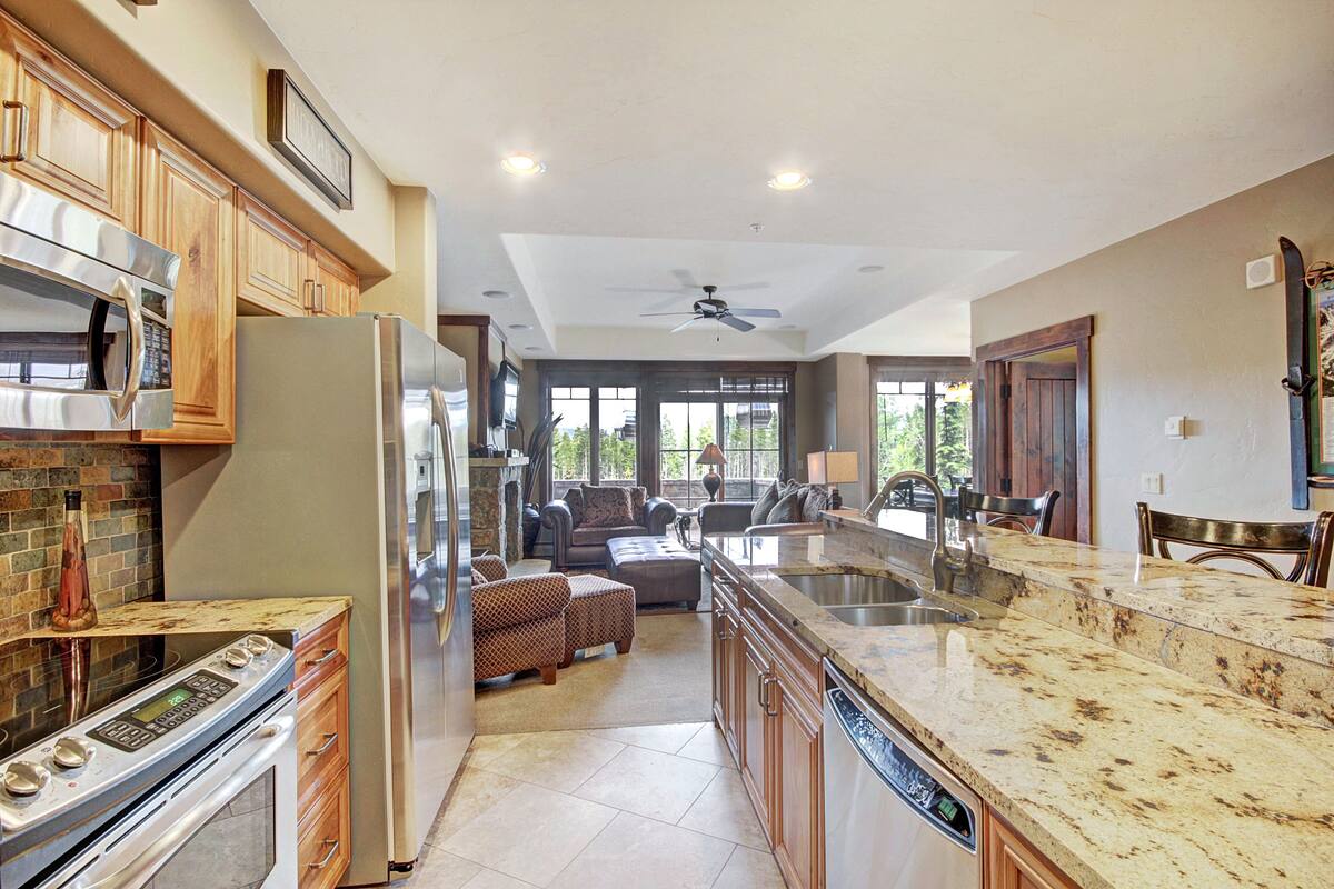 A modern kitchen with stainless steel appliances, a granite countertop, and a dining area with a large island and seating.
