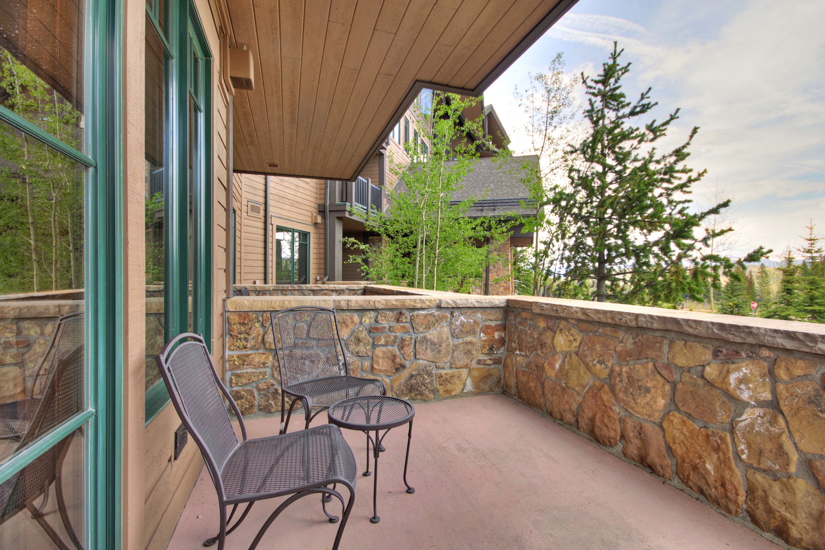 A covered outdoor area with stone walls and metal chairs.