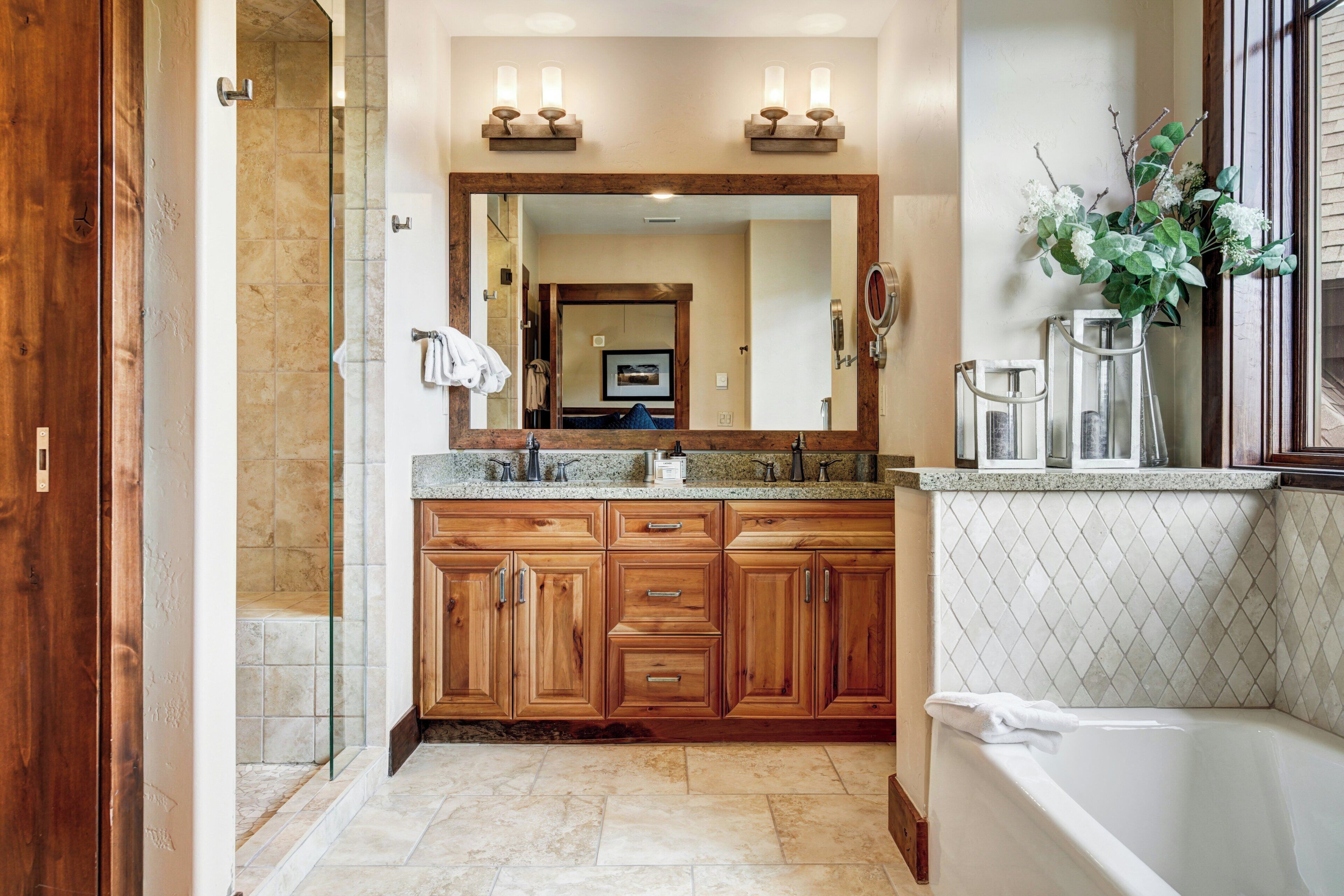 A bathroom with a large wooden vanity, a glass shower enclosure, and a bathtub.