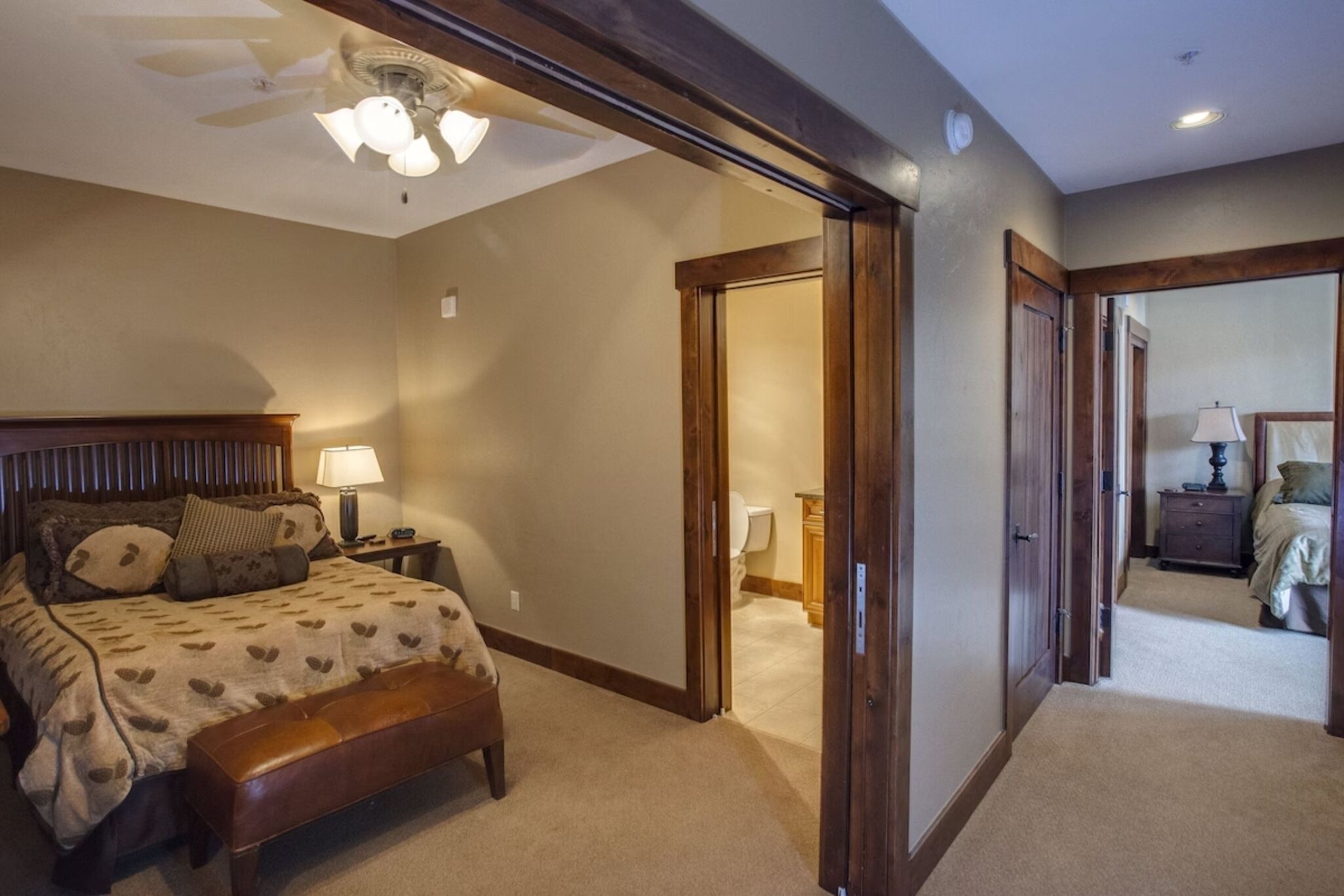 A bedroom with a bed, bedside table, lamp, and a ceiling fan.