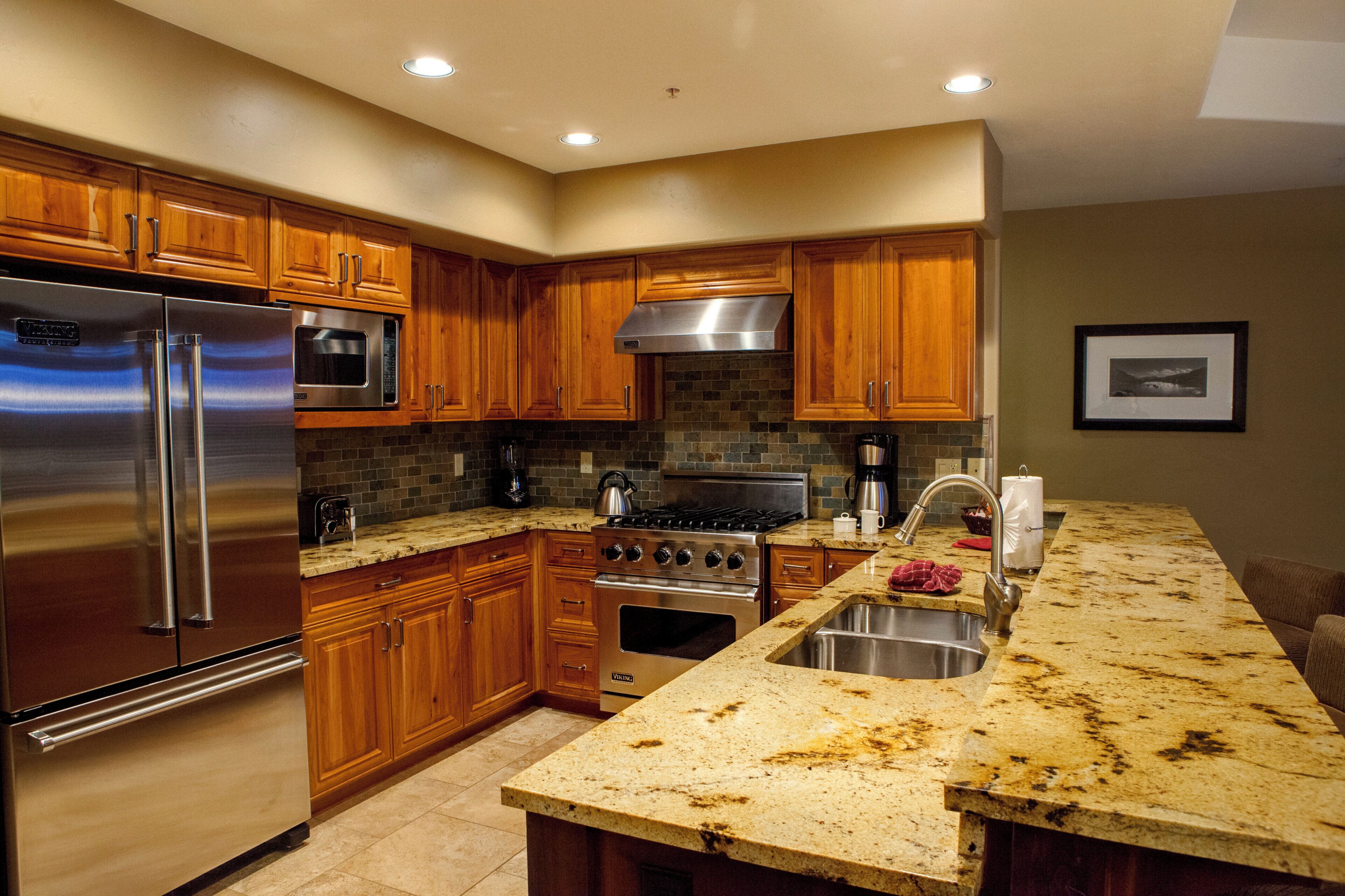 A modern kitchen with wooden cabinets, stainless steel appliances, and a granite countertop.