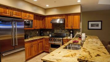 A modern kitchen with wooden cabinets, stainless steel appliances, and a granite countertop.