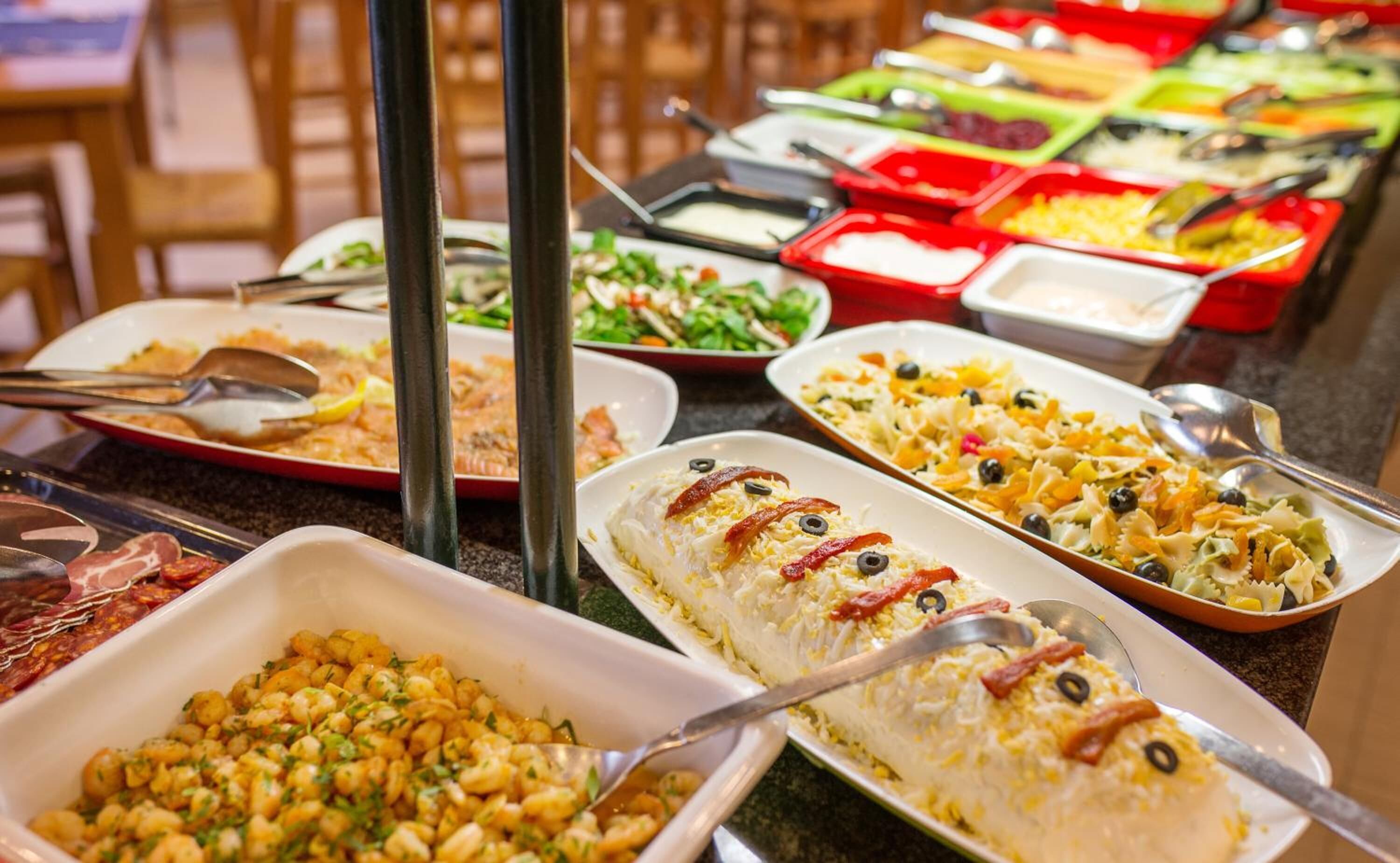 A buffet with various dishes including pasta, salads, and a casserole.